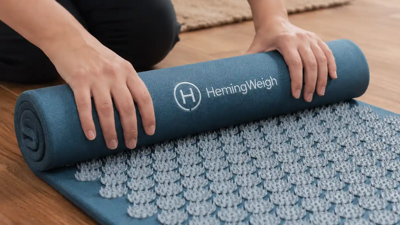 Close-up of hands unrolling the acupressure mat and smoothing it flat on the floor before use