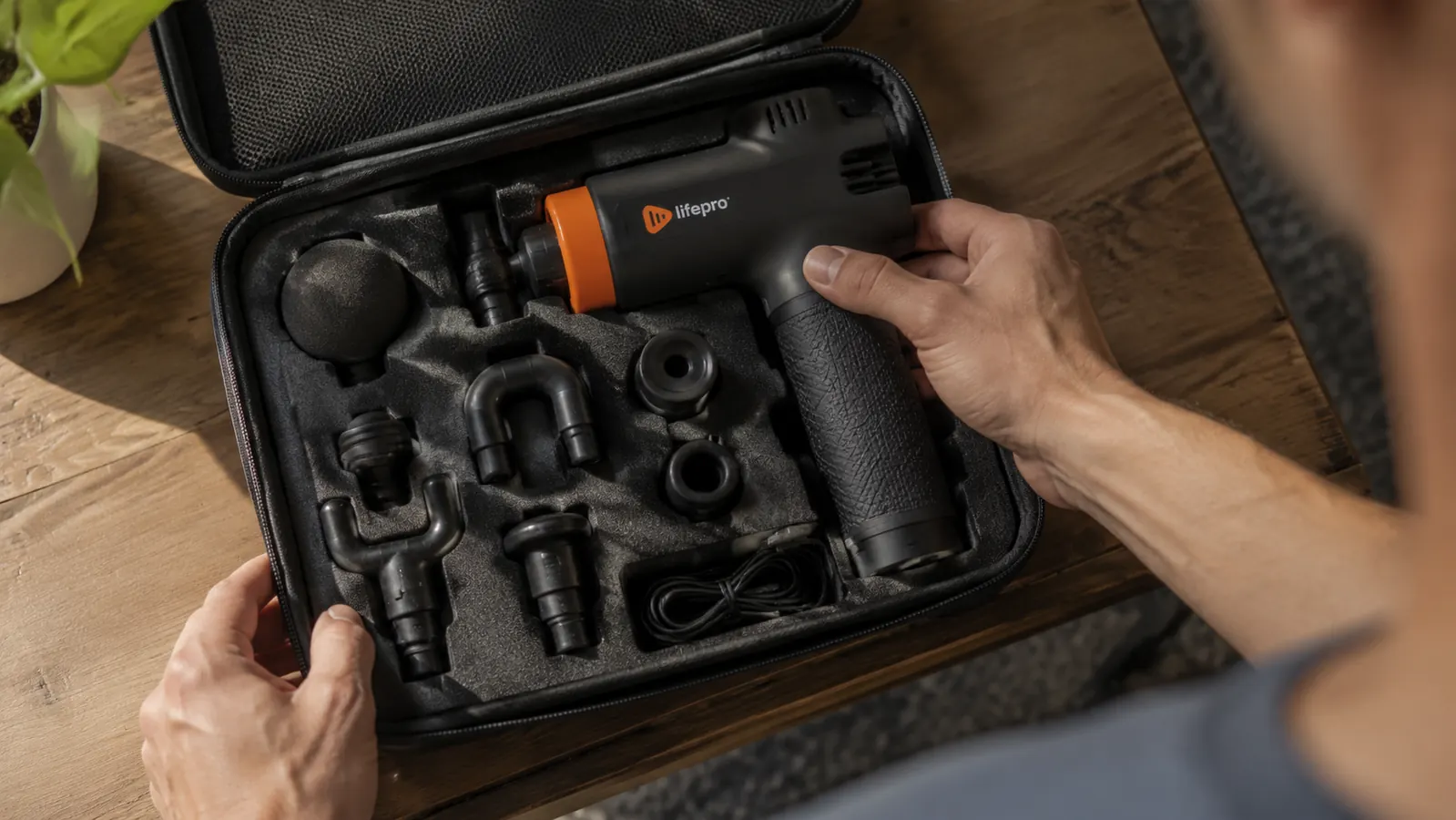 Open massage gun case showing several unused attachment heads still in their foam slots